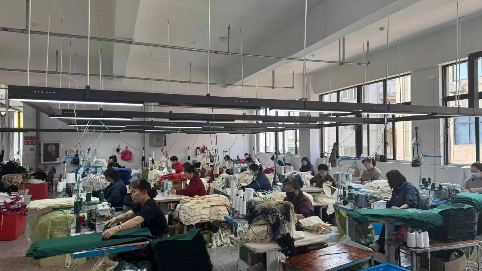 Workers sewing canvas tote bags on industrial sewing machines